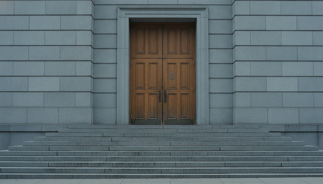 Wide stone steps rising to the heavy closed double doors of a plain civic building, photographed from the street.